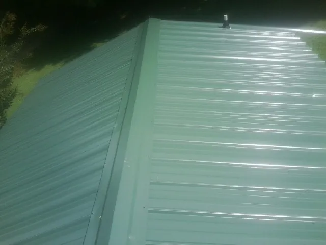 New green metal panels meeting at the ridge of a roof — Flat Roof Repair work by our crew in Hector