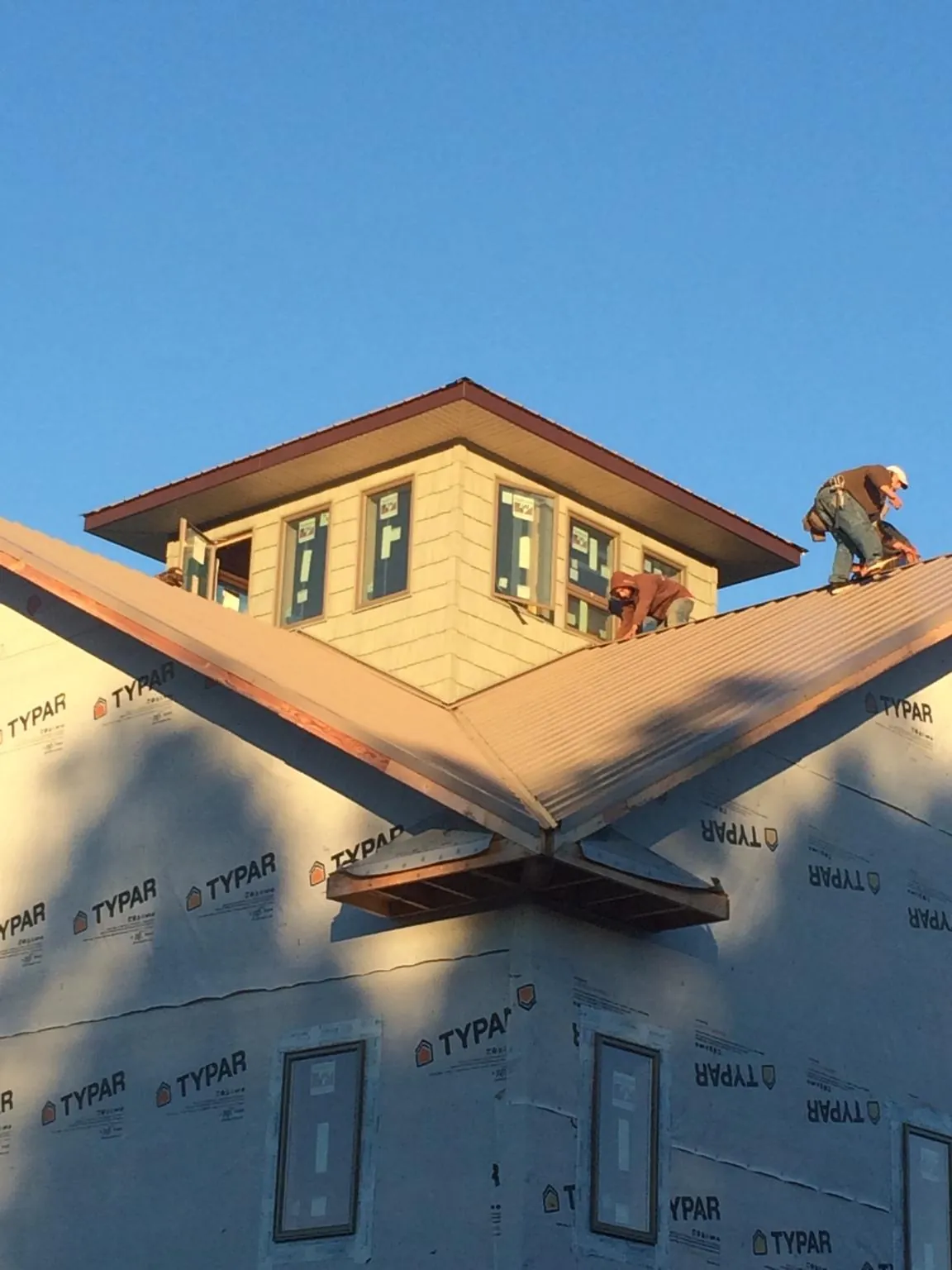 Roofers working around a rooftop cupola on a new metal roof at sunset — Roof Waterproofing in Hector by Roofing Brothers